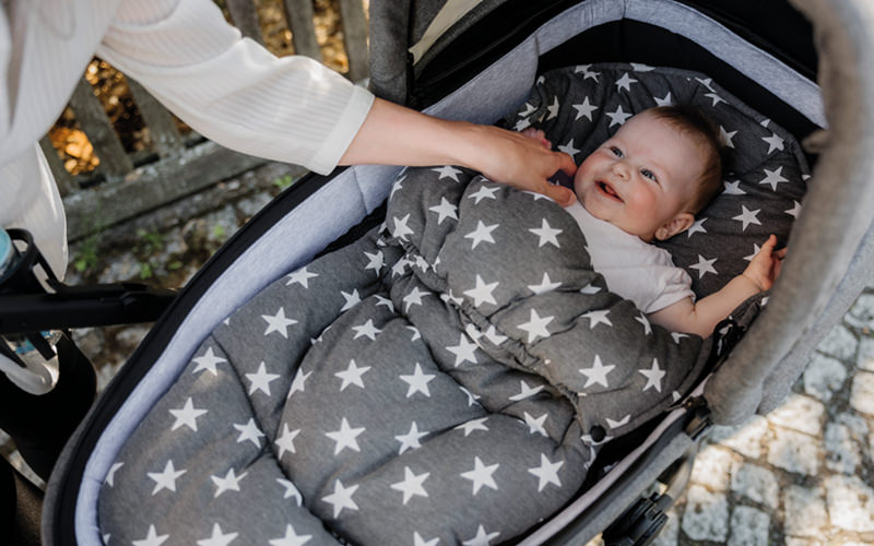 Baby liegt geborgen im Gesslein Kinderwagen