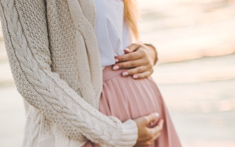 Schwangere Mutter hält liebevoll ihren Babybauch